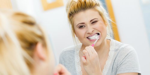 a woman carefully brush her teeth